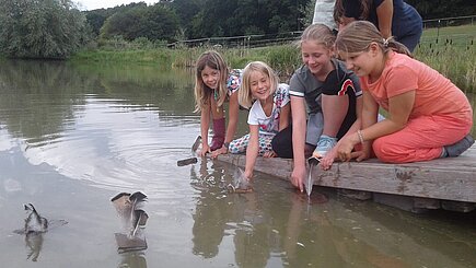 Kinder basteln Schiffchen und lassen sie schwimmen