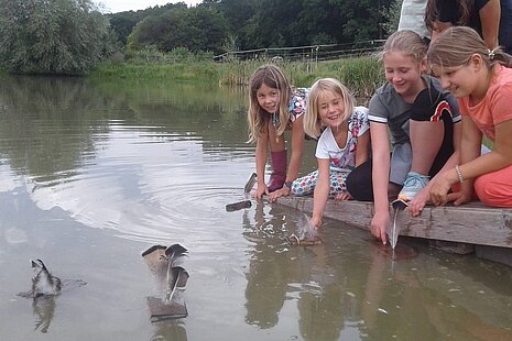 Kinder basteln Schiffchen und lassen sie schwimmen